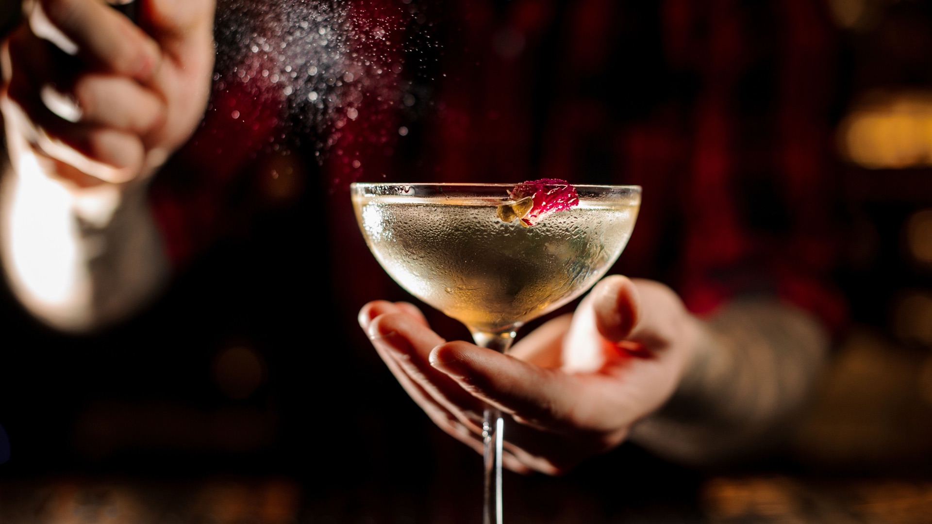 Barman servant un cocktail en coupe décoré d'une fleur comestible